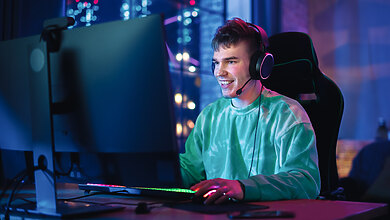 A guy in a sea-green shirt enjoying gaming in his setup.